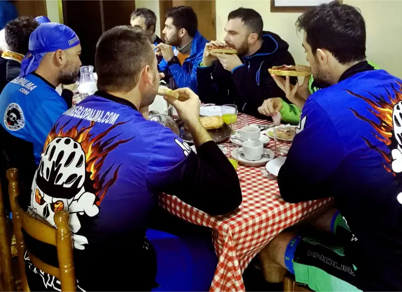 Grupo de ciclistas disfrutando de un desayuno con pan con tomate en la masía Can Micós, Girona.